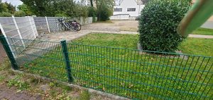 "metal fence in front of lawn, with paved footway behind"