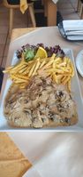 "schnitzel covered in cream sauce and mushrooms, with fries next to it"