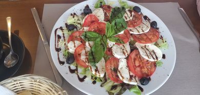 "slices of tomato and mozzarella with lettuce, olives, balsamico vinegar and basil on top"