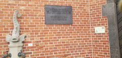 "brick wall with info boards; water well on the left"