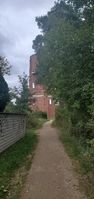 "compacted footway, neighbored by trees, red tower in background"