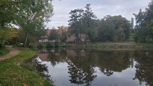 "lake with mirror reflection of houses, trees and cloudy sky"